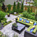 A beautiful small, urban backyard garden featuring a tumbled paver patio, flagstone stepping stones, and a variety of trees, shrubs and perennials add colour and year round interest.