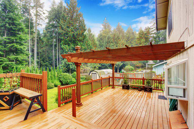 Spacious wooden deck with benches and attached pergola